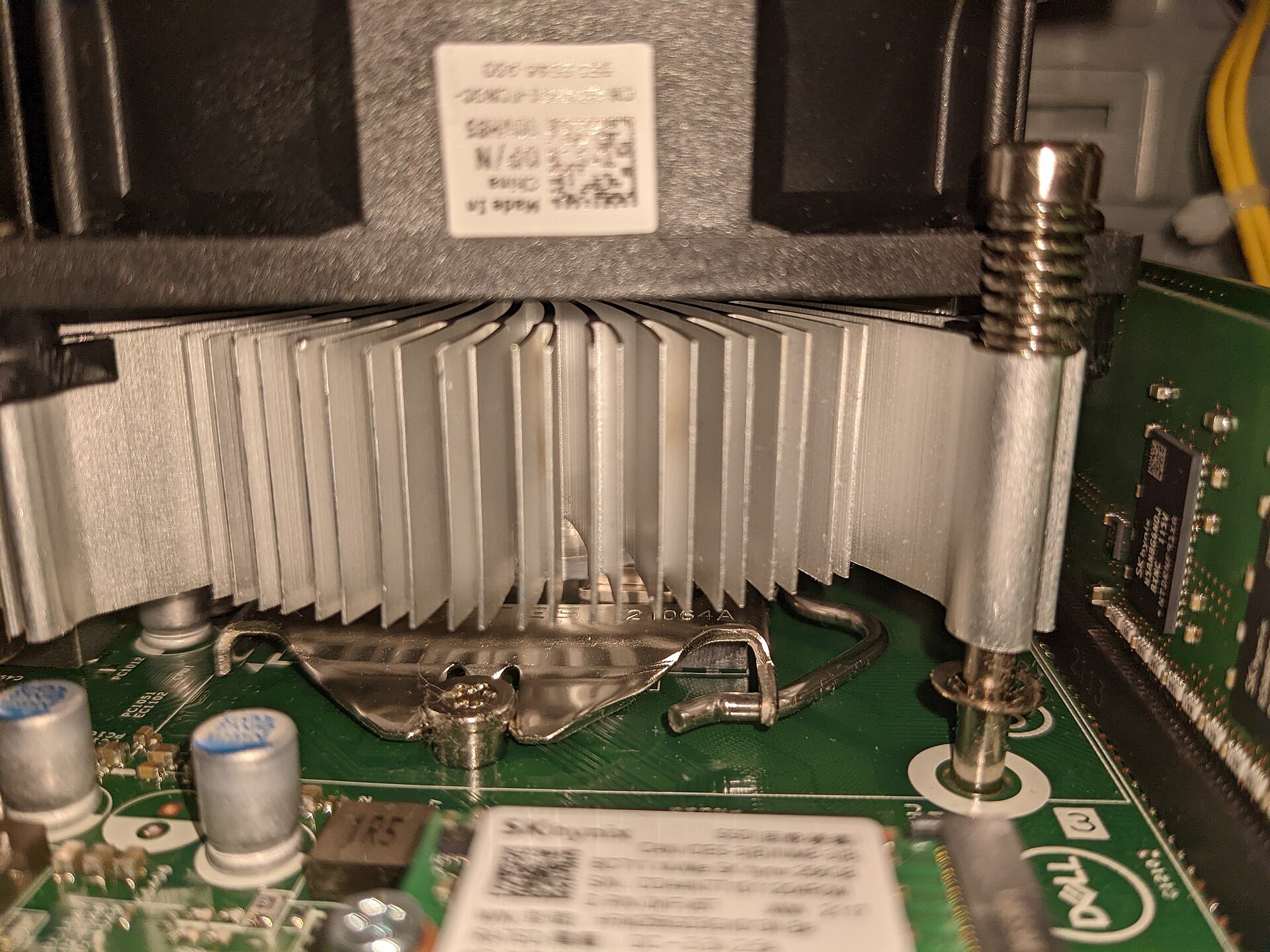 Close-up inside a Dell PC showing the aluminium cooler fins and fan sitting over the CPU on a green motherboard