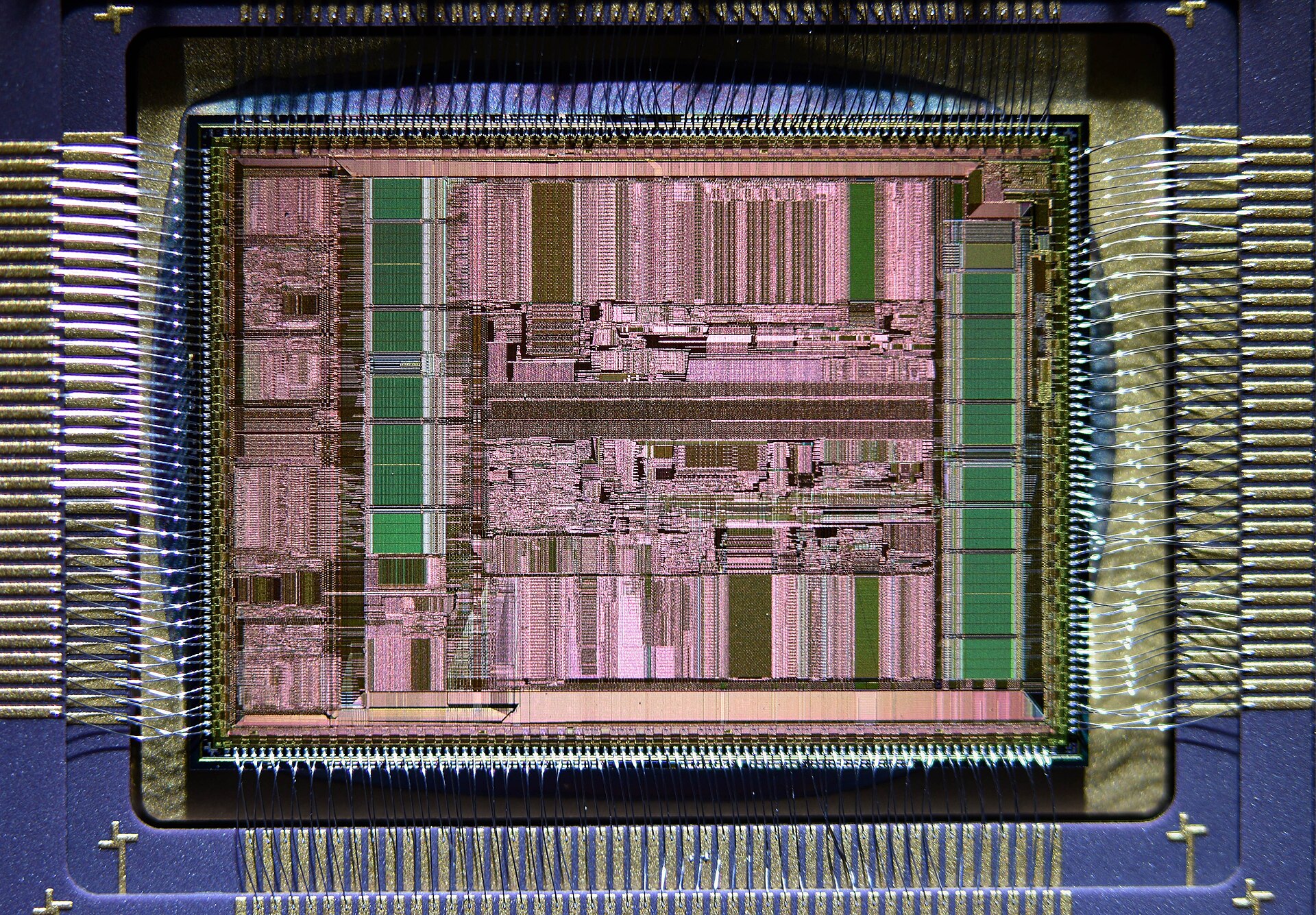 Close-up of a bare silicon CPU chip with gold wires running to its edges