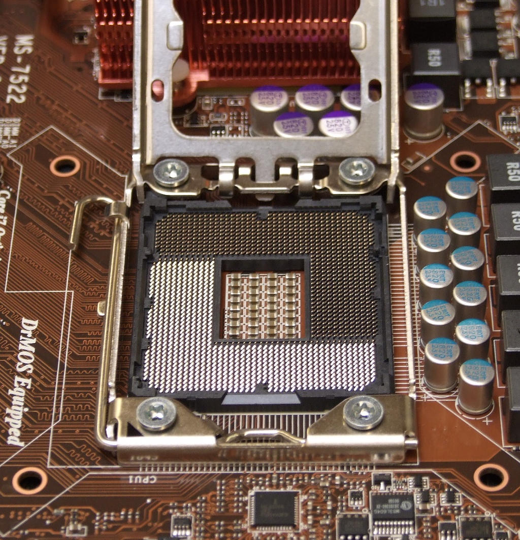An empty CPU socket with a square field of tiny gold pins and a metal frame and lever