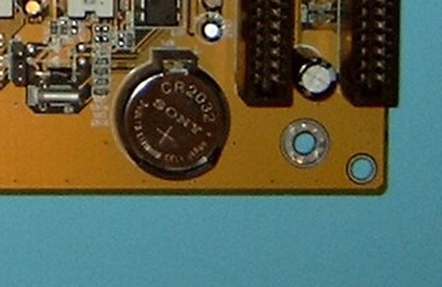 A round silver CR2032 coin battery in a holder on a motherboard