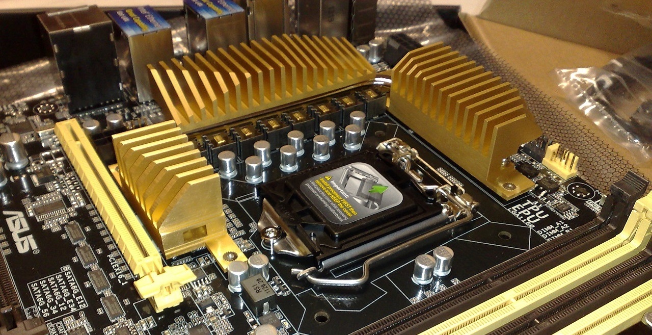 Gold heat sinks next to the CPU socket on a motherboard, covering the voltage regulator