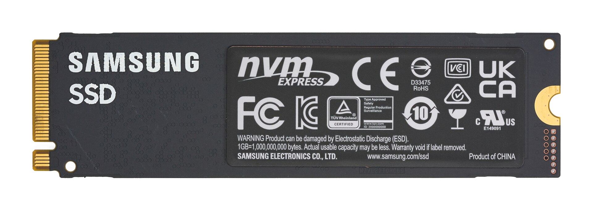 The bottom side of the Samsung 980 PRO SSD showing the Samsung and SSD lettering, a gold connector on the left and a large label with the nvm express logo and many certification marks
