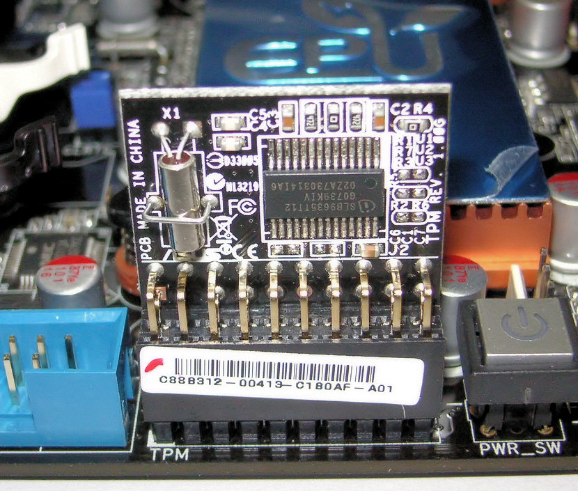 A small black TPM add-on module with an Infineon chip plugged into a pin header marked TPM on a motherboard